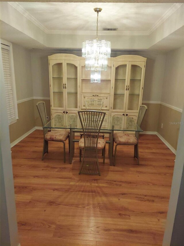 dining space featuring hardwood / wood-style floors, a chandelier, and a tray ceiling