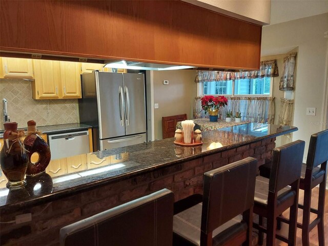 kitchen featuring tasteful backsplash, stainless steel appliances, and dark stone countertops