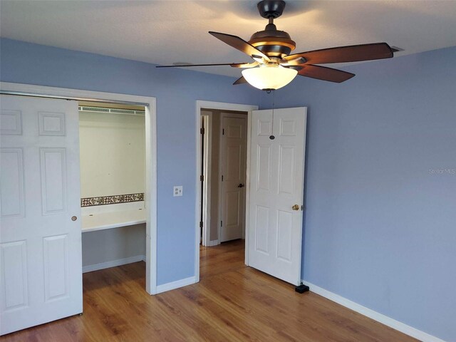 unfurnished bedroom with hardwood / wood-style floors, a closet, and ceiling fan