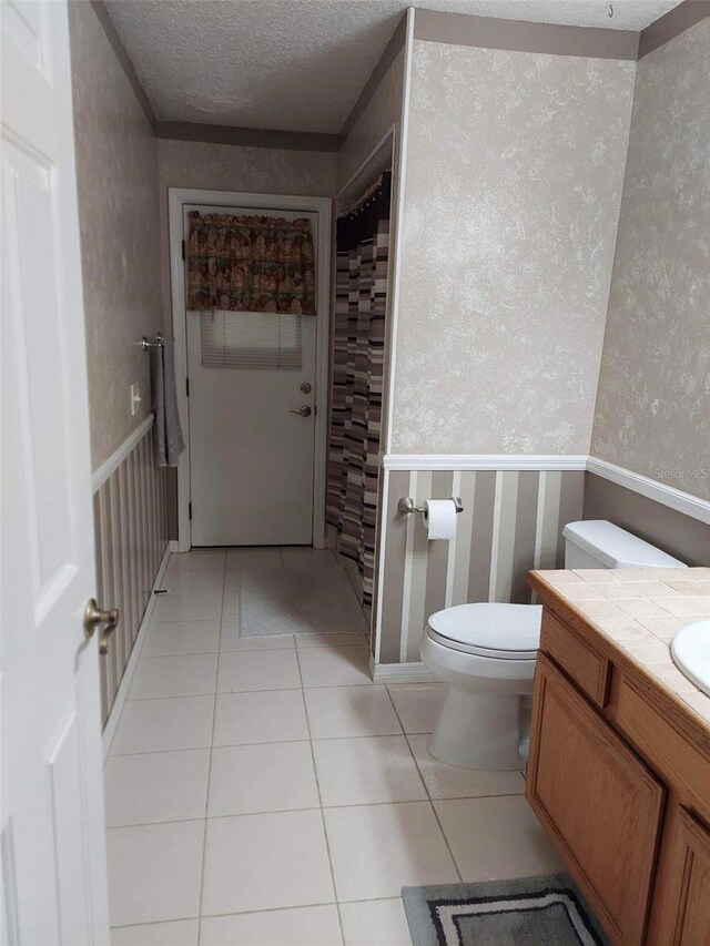 bathroom with vanity, tile flooring, a textured ceiling, and toilet