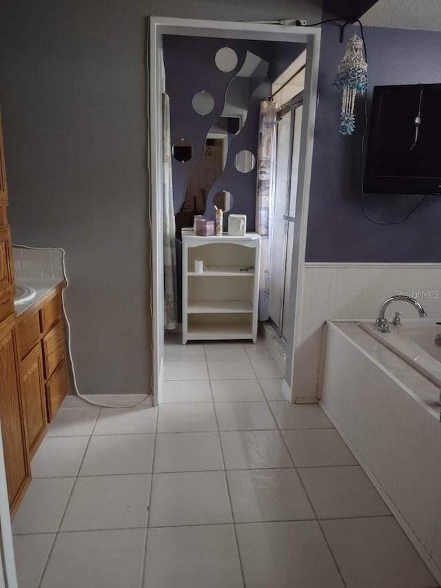 bathroom featuring tile floors, vanity, and a bath to relax in