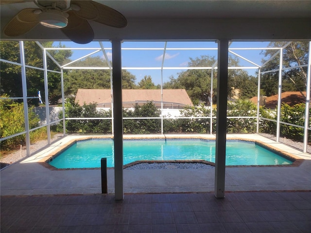 view of pool with glass enclosure, ceiling fan, and a patio