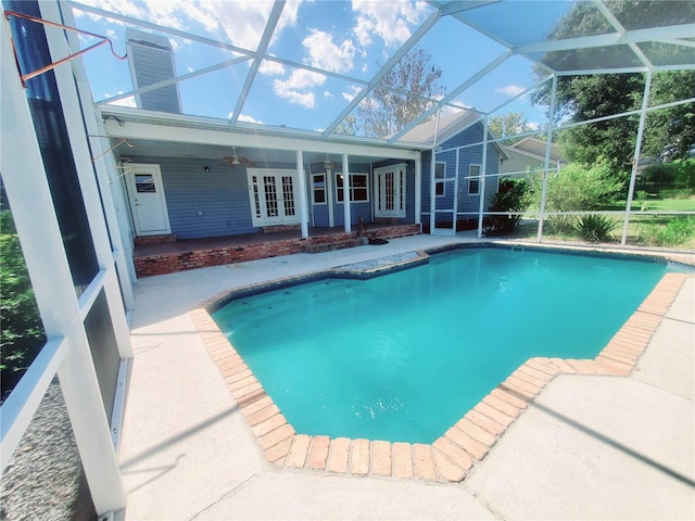 view of swimming pool with glass enclosure, ceiling fan, and a patio