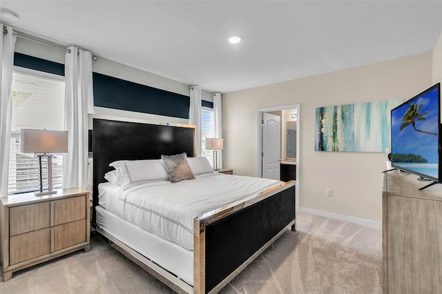 bedroom with light colored carpet, ensuite bathroom, and multiple windows