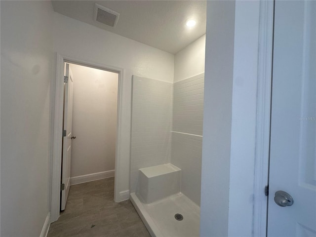 bathroom with a shower, hardwood / wood-style flooring, and a textured ceiling