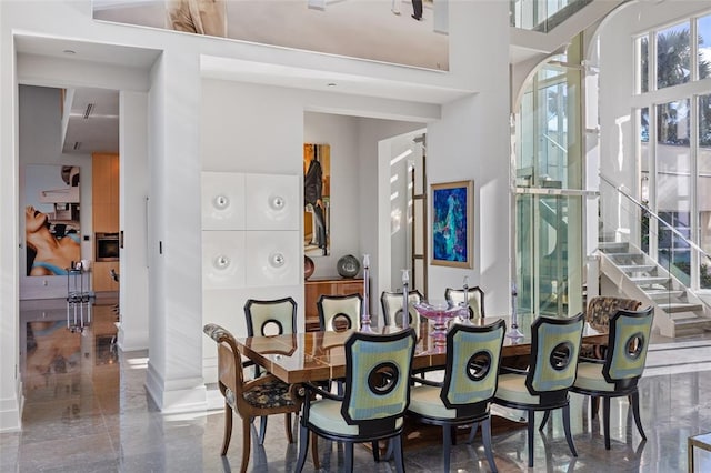 tiled dining area featuring a towering ceiling