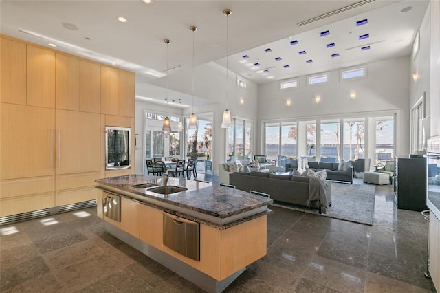 kitchen featuring hanging light fixtures, light brown cabinets, and a kitchen island with sink