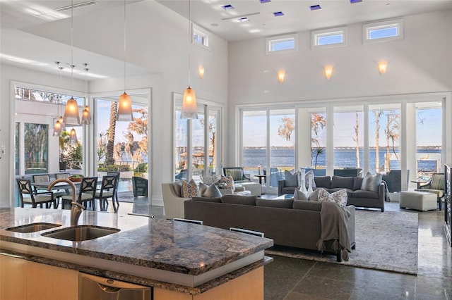 living room with a water view, a towering ceiling, and sink