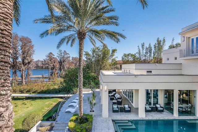 exterior space featuring a balcony, a patio area, and a water view