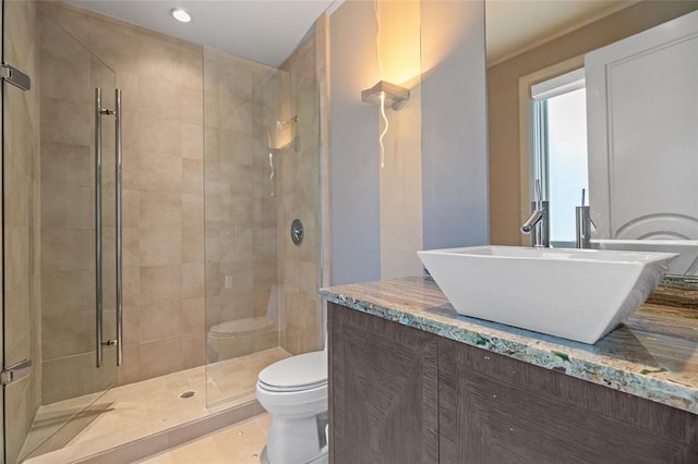 bathroom featuring toilet, vanity, a shower with shower door, and tile flooring