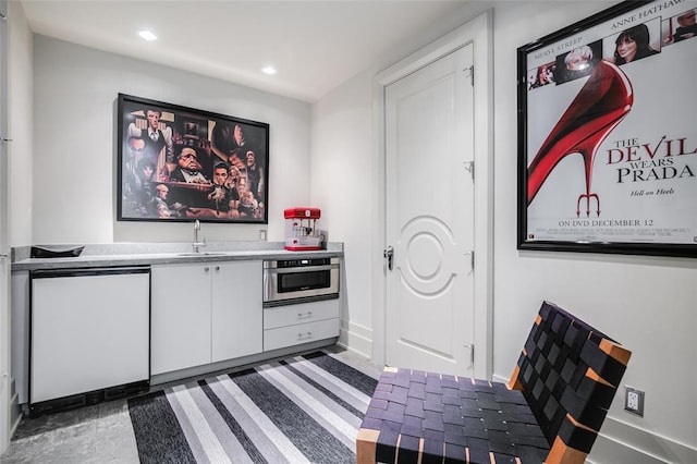 interior space with white cabinets, oven, and sink