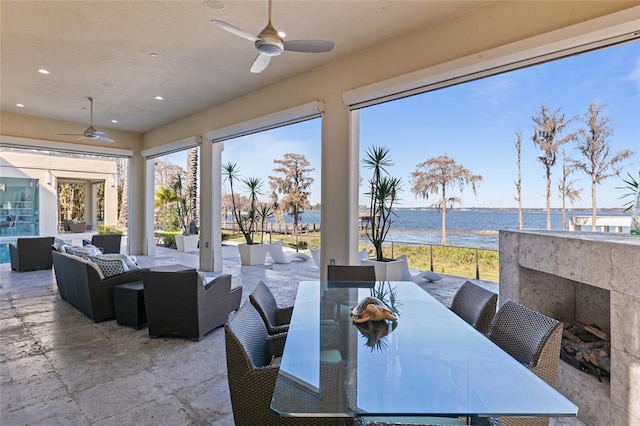 view of terrace with an outdoor living space, ceiling fan, and a water view