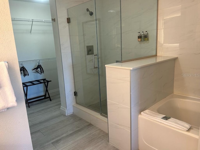 bathroom featuring separate shower and tub and wood-type flooring