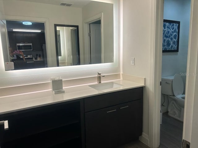 bathroom featuring toilet, hardwood / wood-style floors, and vanity