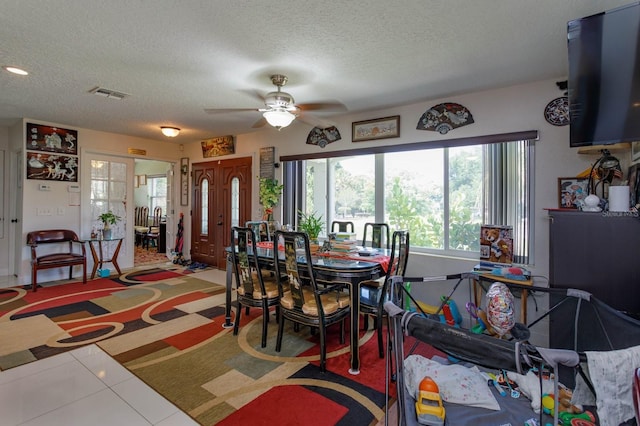 dining area featuring ceiling fan, visible vents, a textured ceiling, and tile patterned floors