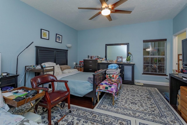 bedroom with ceiling fan, baseboards, a textured ceiling, and wood finished floors