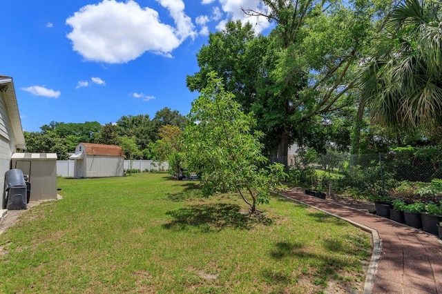 view of yard with a fenced backyard, an outdoor structure, and a storage unit