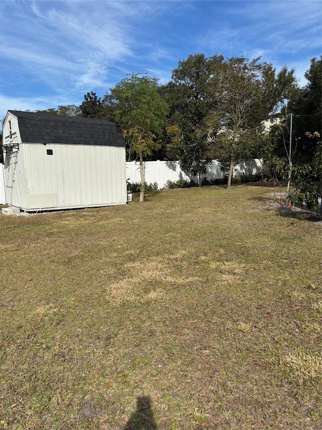 view of yard featuring fence, a storage unit, and an outbuilding