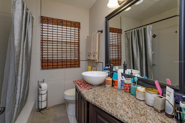 full bathroom featuring vanity, toilet, and tile walls