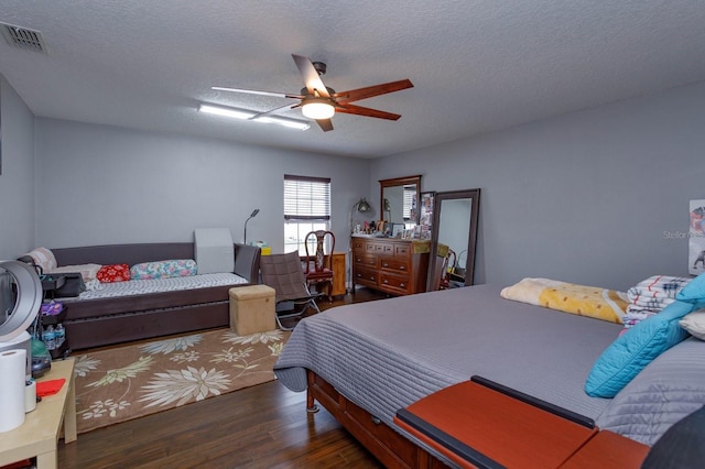 bedroom with ceiling fan, dark hardwood / wood-style flooring, and a textured ceiling