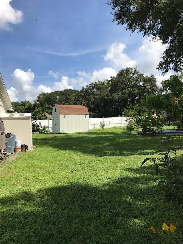 view of yard with an outbuilding, fence, and a storage shed