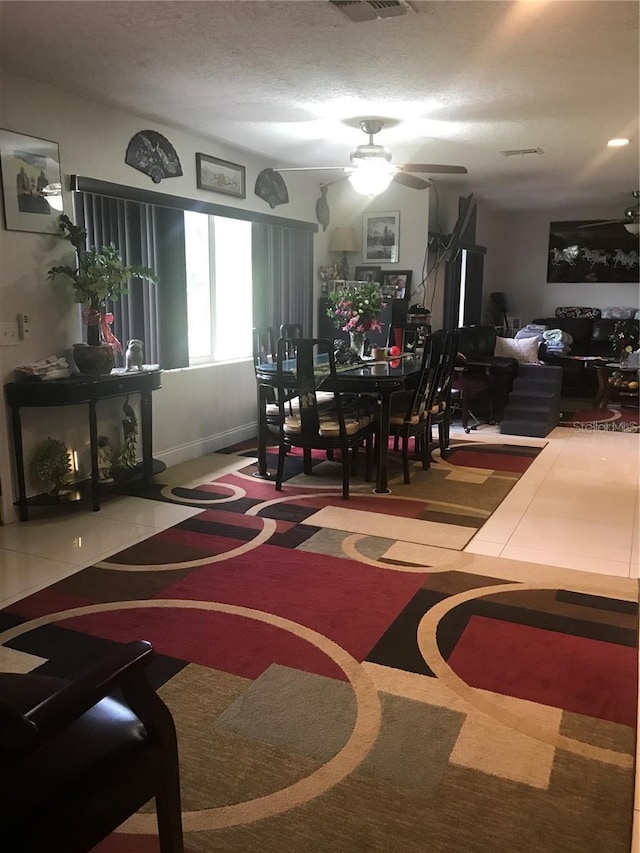 dining room with a textured ceiling, ceiling fan, visible vents, and tile patterned floors