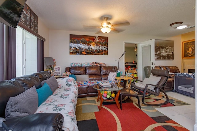 tiled living room with ceiling fan and a textured ceiling