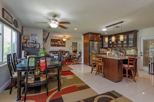 dining room featuring ceiling fan, a textured ceiling, and light tile patterned flooring