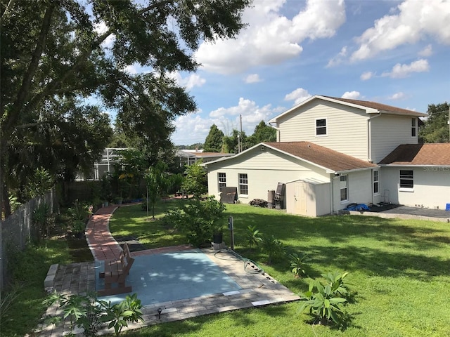 back of house featuring a patio, a lawn, and a shed