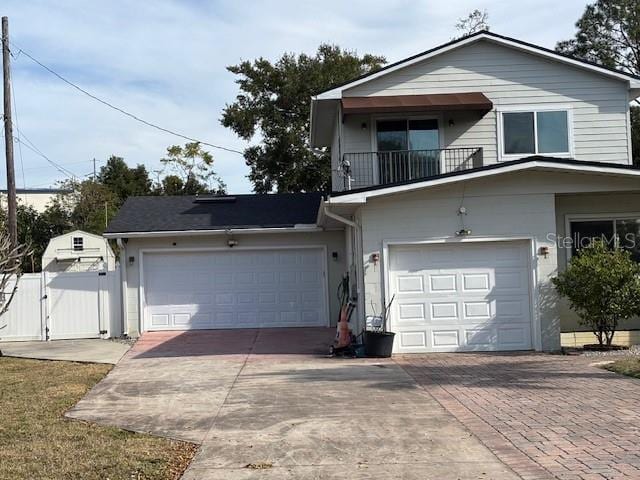 traditional-style home with a balcony, driveway, fence, and a gate