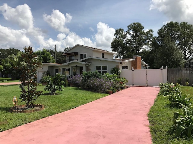 view of front of house with driveway, a front yard, fence, and a gate