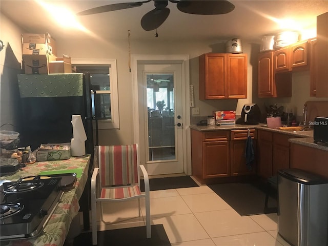 kitchen with light tile patterned floors, stainless steel gas stovetop, sink, and ceiling fan