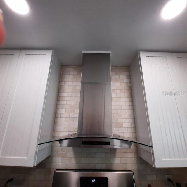 interior space featuring tasteful backsplash, wall chimney exhaust hood, and dark tile flooring