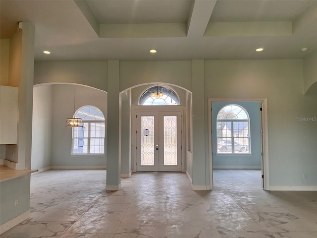 foyer entrance with a raised ceiling, a towering ceiling, and a notable chandelier