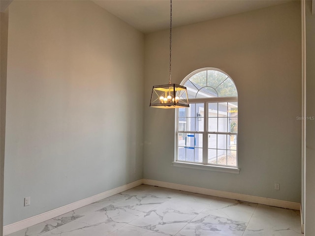 spare room featuring a notable chandelier and plenty of natural light