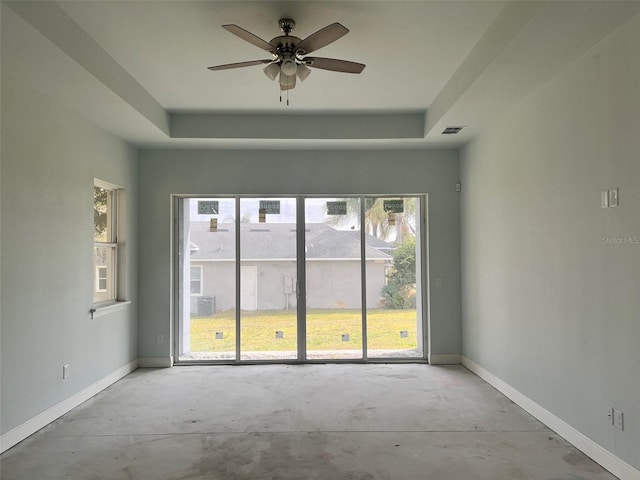 spare room featuring a tray ceiling, a wealth of natural light, and ceiling fan