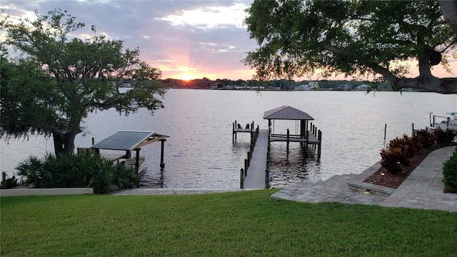 view of dock with a water view and a yard