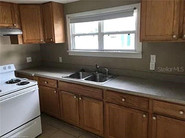 kitchen featuring white gas range, light tile floors, and sink