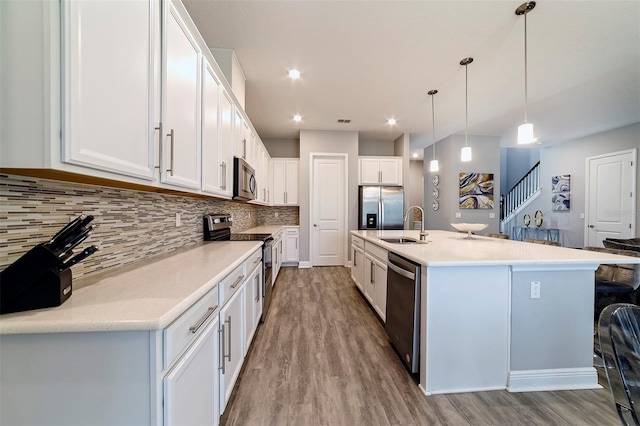 kitchen with white cabinets, hanging light fixtures, light hardwood / wood-style floors, and appliances with stainless steel finishes