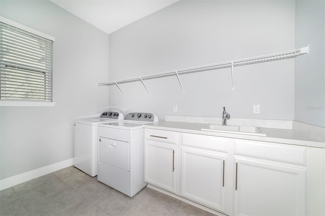 washroom featuring washing machine and dryer, light tile floors, cabinets, and sink