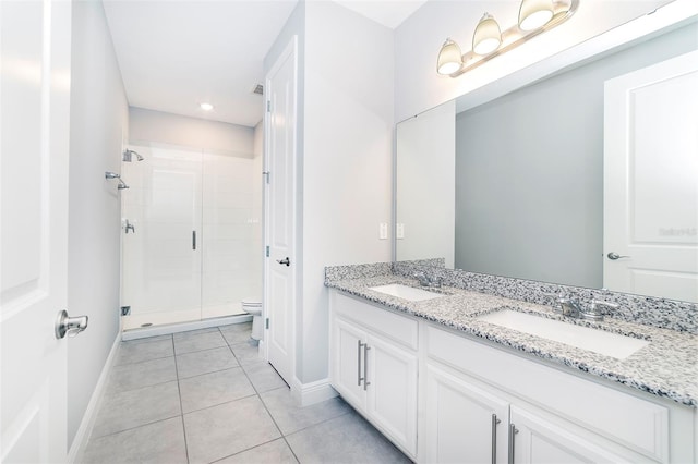 bathroom featuring toilet, large vanity, a shower with shower door, dual sinks, and tile floors