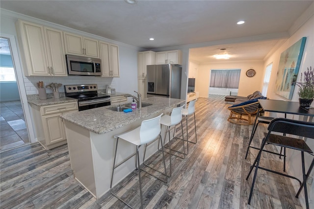 kitchen with tasteful backsplash, wood-type flooring, appliances with stainless steel finishes, and sink