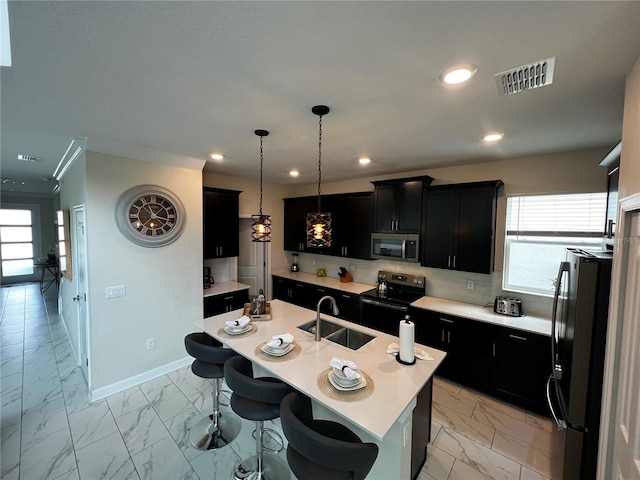 kitchen featuring an island with sink, stainless steel appliances, sink, and light tile floors