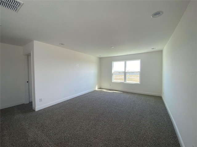 unfurnished room featuring dark colored carpet