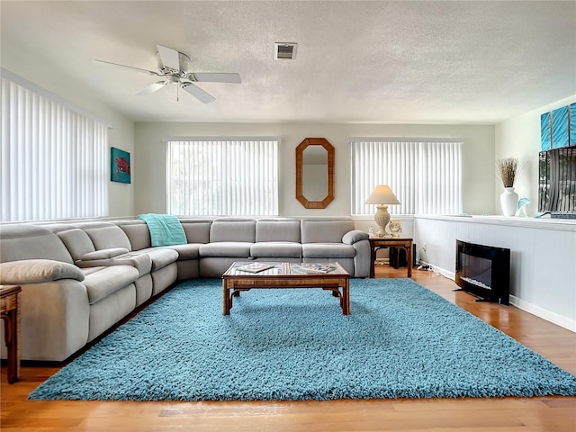 living room featuring ceiling fan, light wood-type flooring, and a wealth of natural light