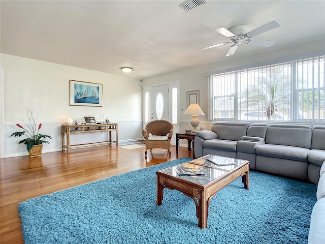 living room featuring ceiling fan, wood-type flooring, and a wealth of natural light