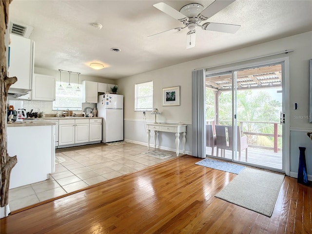 kitchen with white cabinetry, light hardwood / wood-style floors, a healthy amount of sunlight, and white refrigerator