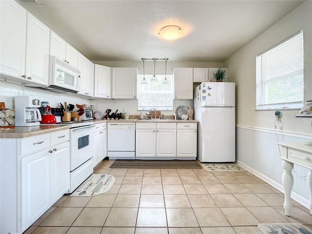 kitchen with decorative light fixtures, white appliances, a healthy amount of sunlight, and white cabinets