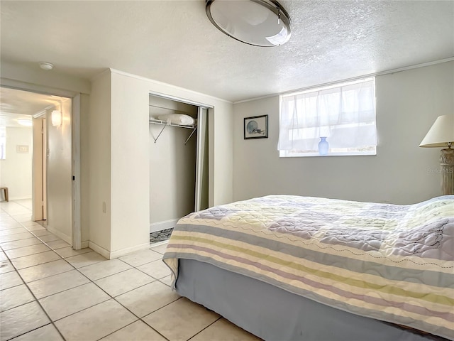 bedroom with a closet, a textured ceiling, light tile flooring, and ornamental molding