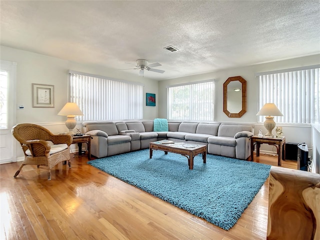 living room featuring a textured ceiling, light hardwood / wood-style floors, and ceiling fan